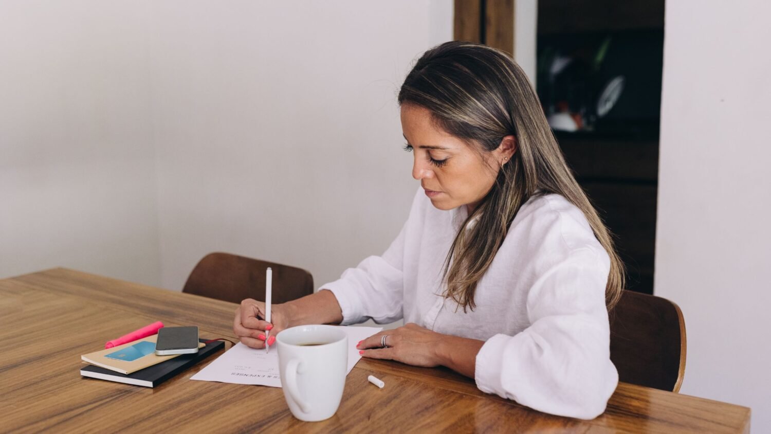 woman planning how to get in the mood on the wooden desk with a white cup of coffee next to her