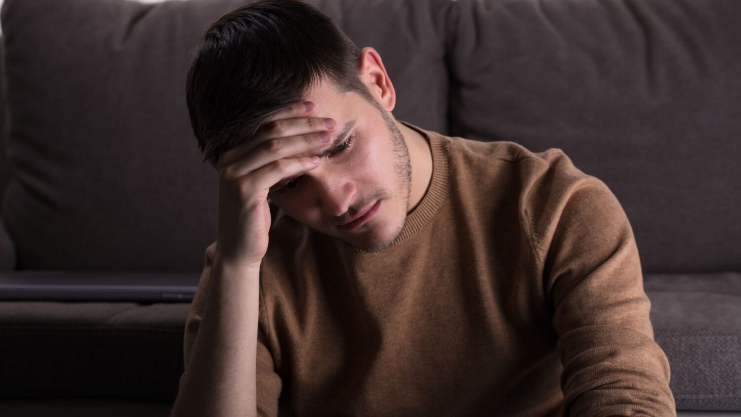 sad man sitting in a dark room representing red flags in a man