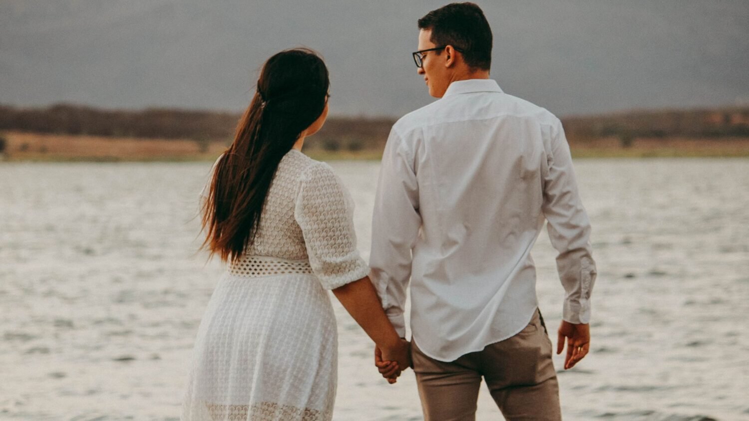 newlywed couple holding hands on the beach during first night in their marriage