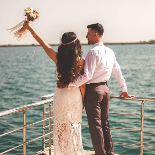 married couples in the wedding clothes on a boat, sea in the background